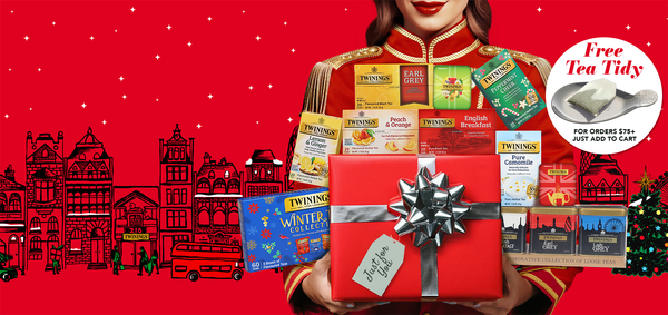 Person holding a gift box with Twinings tea packages on a red background